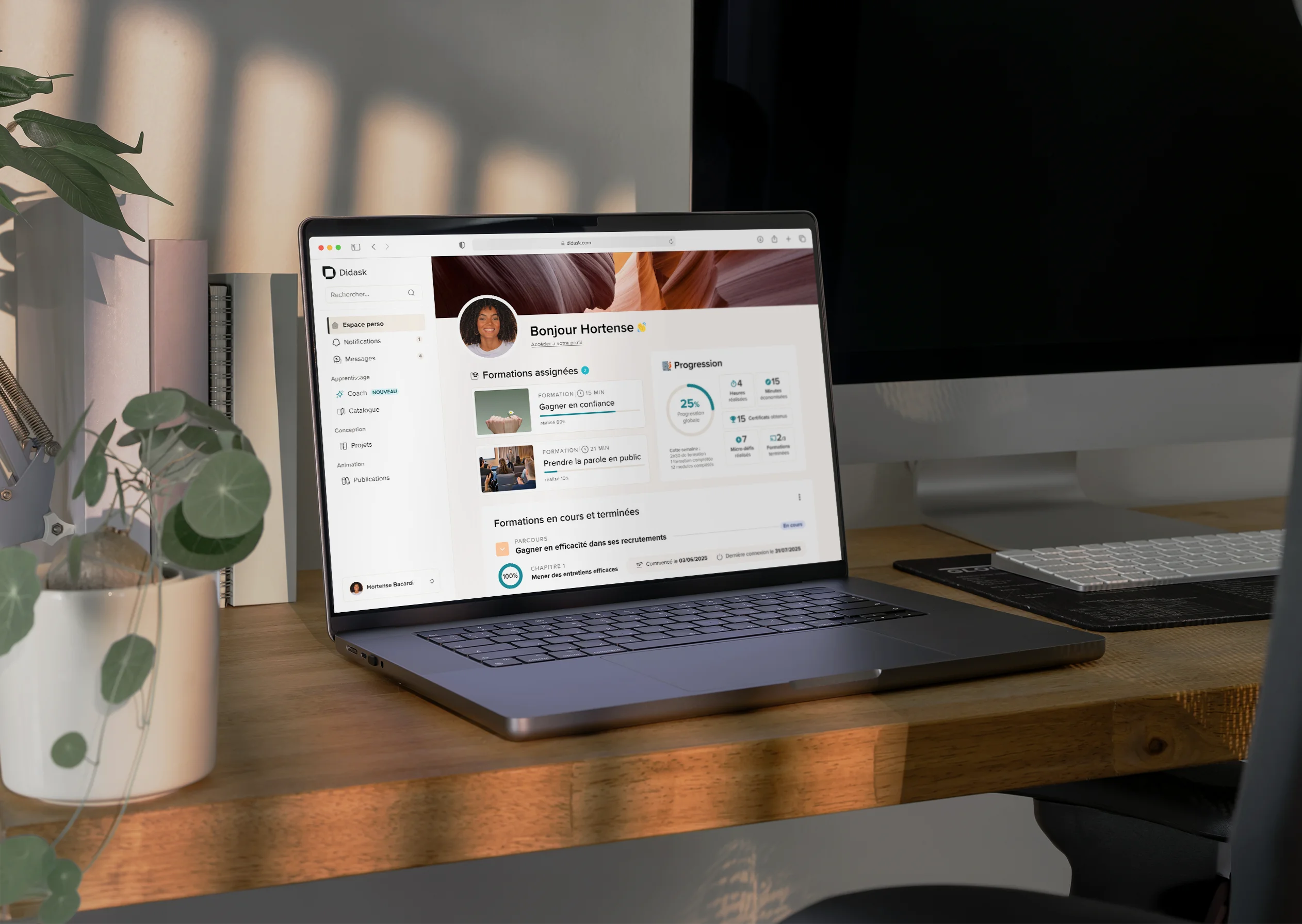 Ordinateur portable affichant un tableau de bord de formation en ligne avec les progrès et les cours assignés, posé sur une table en bois à côté d'un carnet orange.