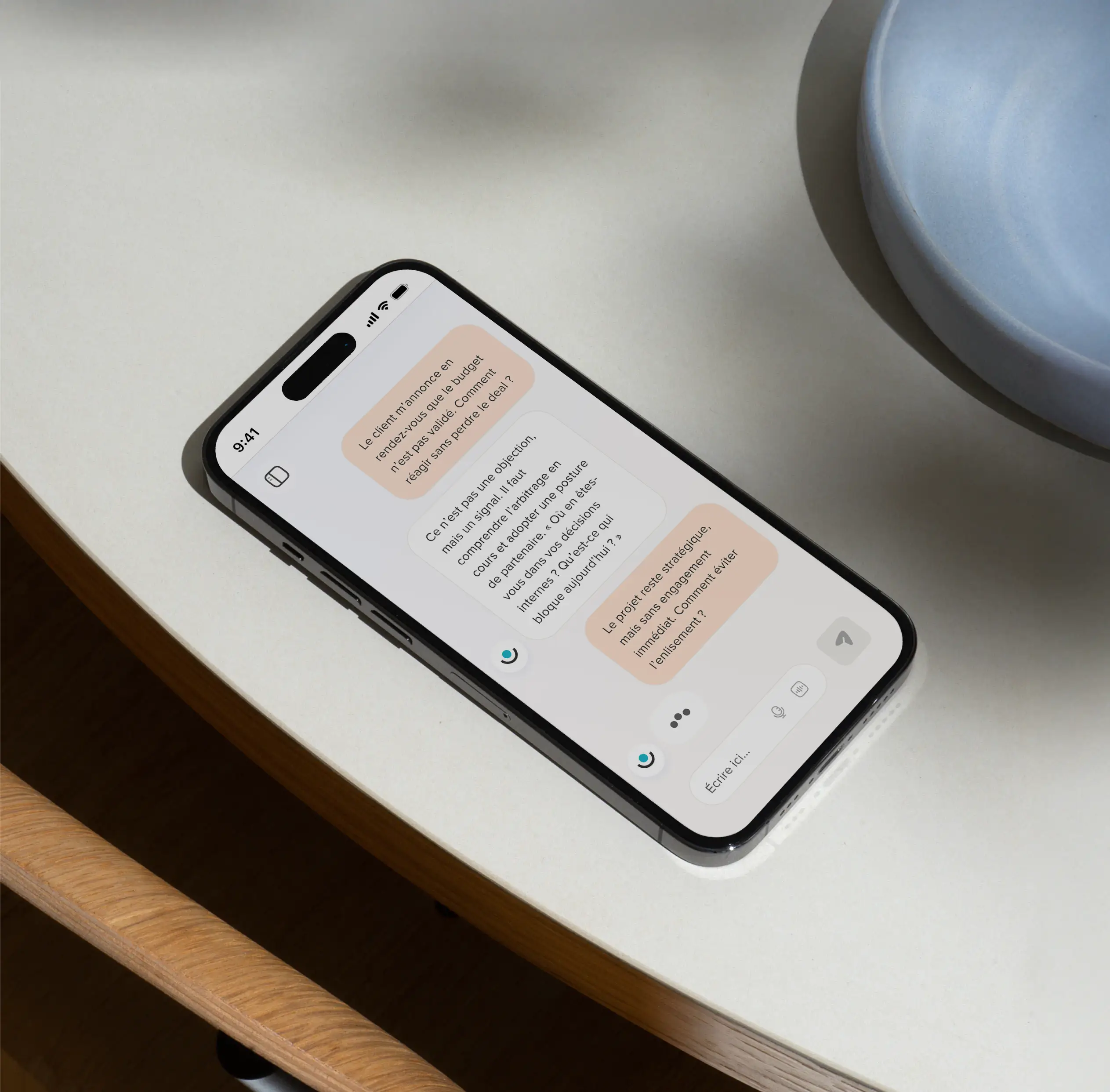 Téléphone posé sur une table avec une conversation de chat en français à l'écran.
