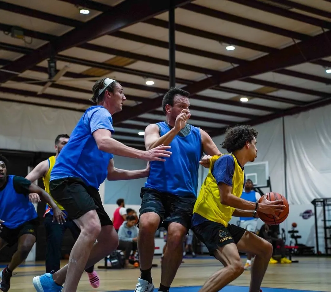 Indoor basketball game with players in blue and yellow jerseys actively competing for the ball.