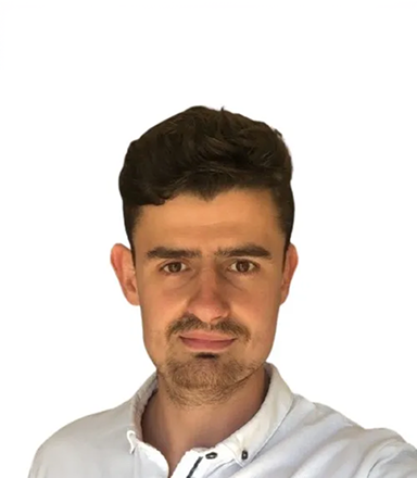 Young man with short dark hair and a trimmed beard wearing a white collared shirt, looking at the camera against a white background.