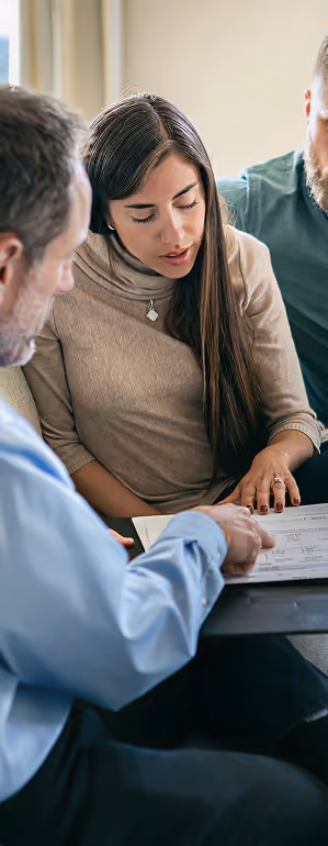 Two men and a woman reviewing documents together at a table in a meeting.