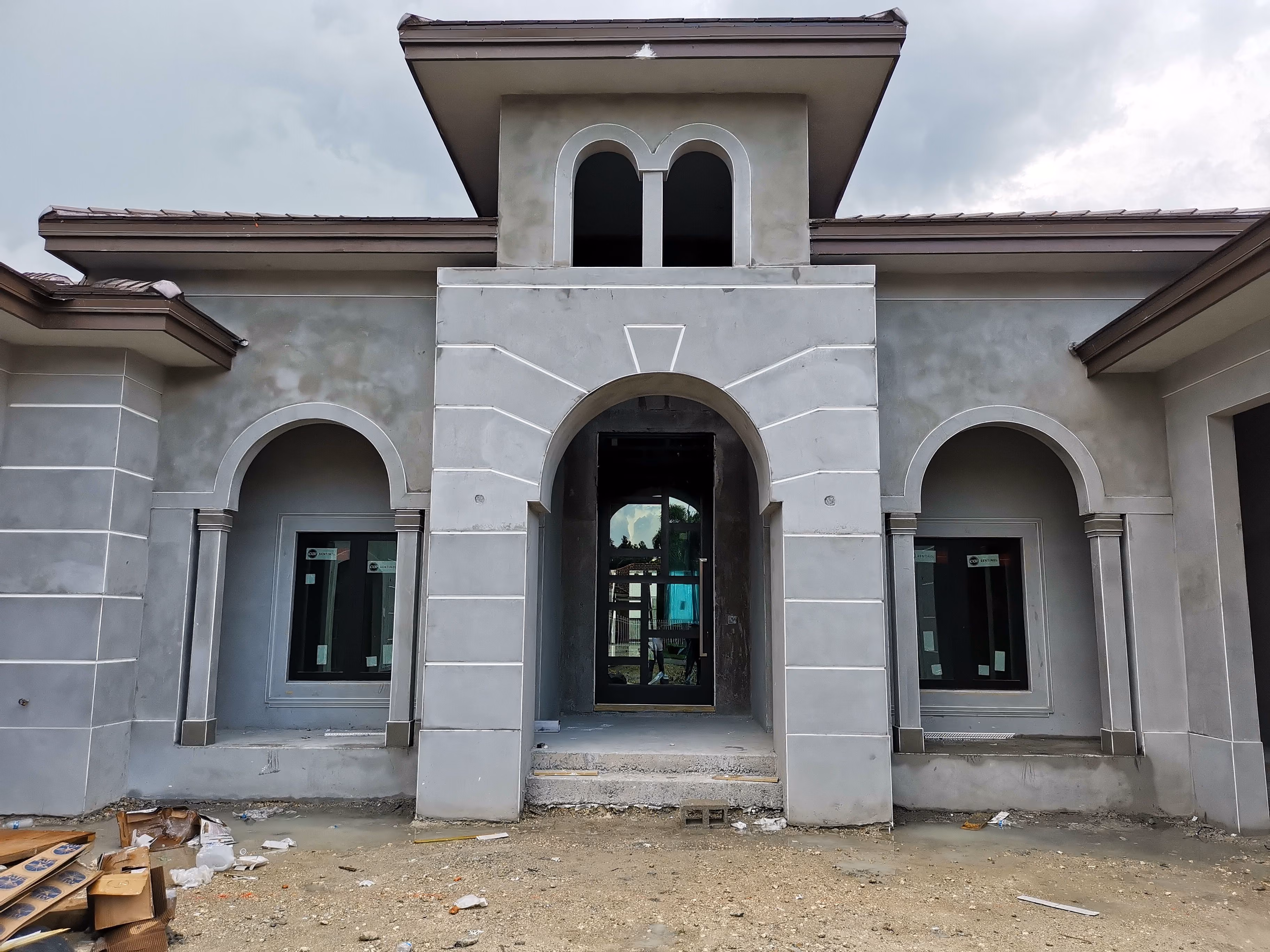 Unfinished concrete building façade with arched impact doors
