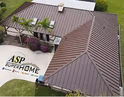 Aerial view of a large standing seam metal roof on a house surrounded by greenery and colorful plants.