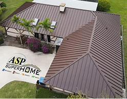 Aerial view of a large standing seam metal roof on a house surrounded by greenery and colorful plants.