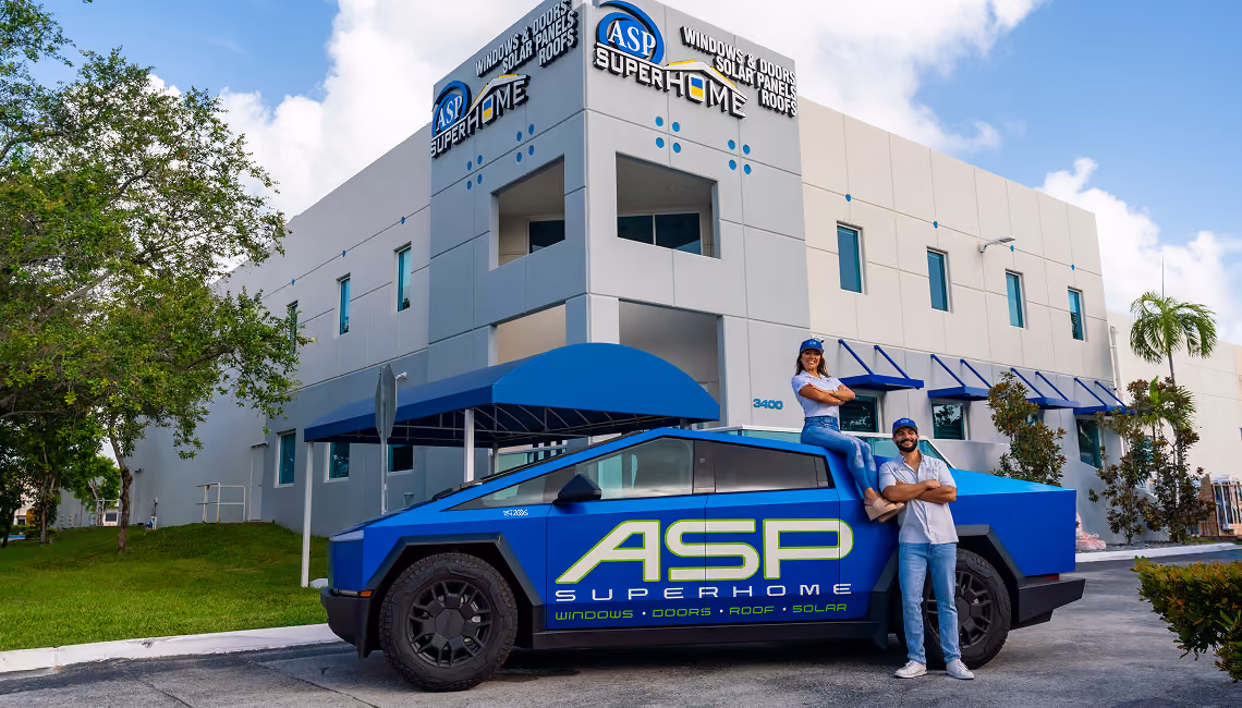 Two people posing next to a blue ASP Superhome branded electric truck outside a modern ASP Superhome building.
