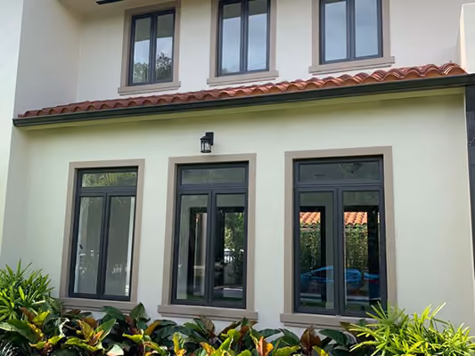 Two-story house exterior with beige walls, three large ground-floor glass windows