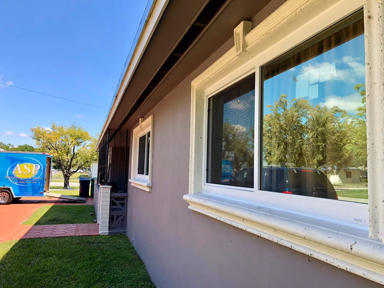 Exterior view of a house wall with two white-framed glass windows