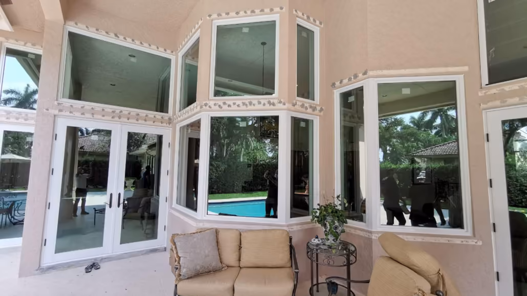 Patio area with large glass windows and glass doors overlooking a swimming pool