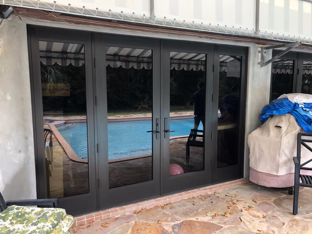 Glass patio sliding glass doors reflecting a swimming pool and surrounding outdoor area