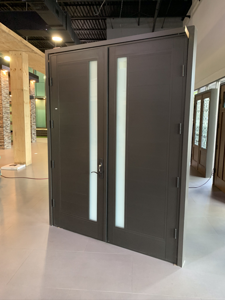 Modern dark double doors with vertical frosted glass panels in an indoor showroom.