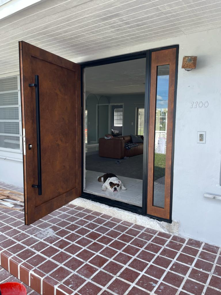 Brown entry door open showing a bulldog lying on the white tiled entry with a brown couch inside the living room.