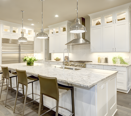 Modern kitchen with white cabinets, stainless steel appliances, marble island with three brown chairs, pendant lights, and decorative plants.