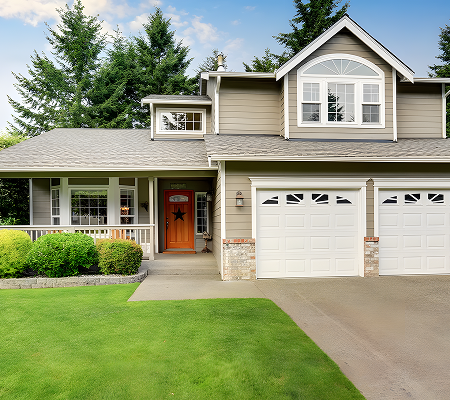 Modern two-story house with a gray exterior, front porch, green lawn, and two white garage doors.