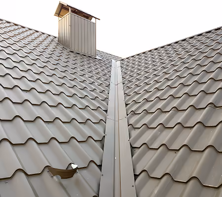 Metal tiled roof with a chimney and a central metal valley flashing.