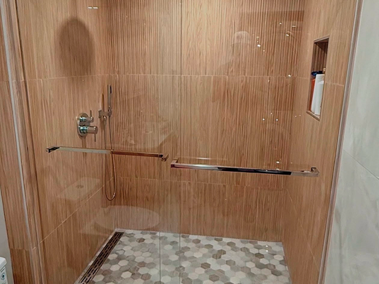 Modern walk-in shower with wood-patterned walls, glass door, and hexagonal tile floor.
