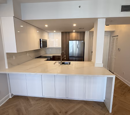Modern kitchen with white marble island, stainless steel appliances, and wood accent cabinets.