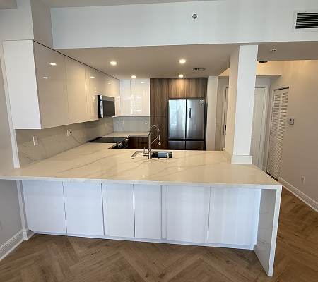 Modern kitchen with white marble island, stainless steel appliances, and wood accent cabinets.
