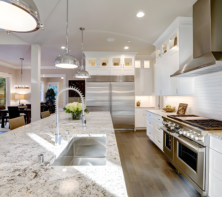 Bright modern kitchen with marble island, stainless steel appliances, white cabinetry, and wooden floor.