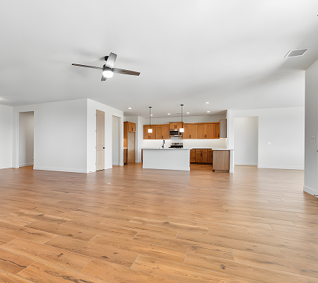 Spacious modern kitchen with wooden cabinets, white island, stainless steel appliances, and hardwood floors.