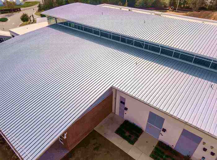 A professional commercial roofing project with a black standing seam metal roof installation