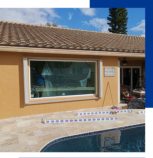 A house with beige exterior and a tiled roof next to a swimming pool, featuring a large window with torn protective film and a sign reading 'Sleeping Destination'.