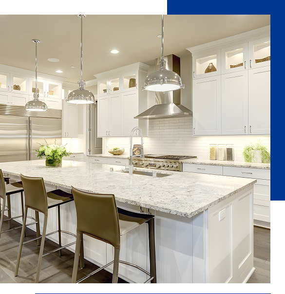 Modern kitchen with a large white marble island, pendant lights, stainless steel appliances, and white cabinets.