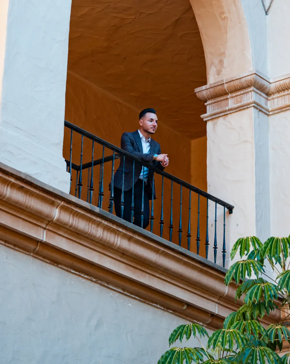 Man leaning on a balcony railing inside a classic architectural space