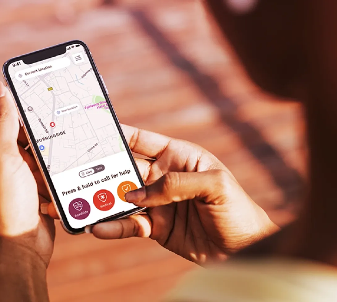 Person holding a smartphone showing a location map with a press-and-hold help button and robbery and medical options