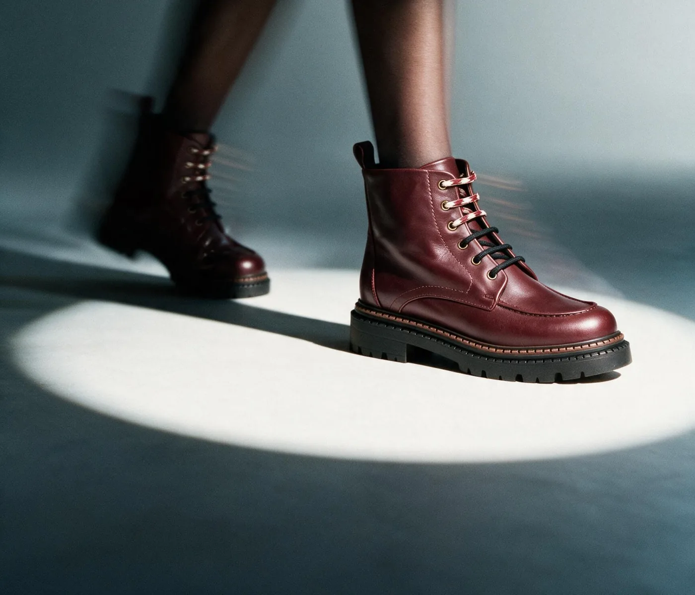 Botas granate caminando bajo un foco de estudio