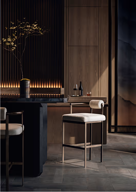 Modern bar stool with light upholstery and metal frame next to a dark bar counter with a vase holding a small branch, set in a dimly lit room with wooden panel walls and soft ambient lighting.