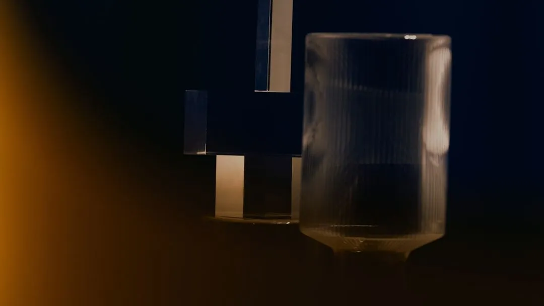 Close-up of two translucent, geometric glass objects against a dark background with warm lighting on the left.