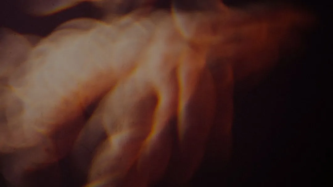 Blurred close-up of a human hand with warm, orange and brown lighting.