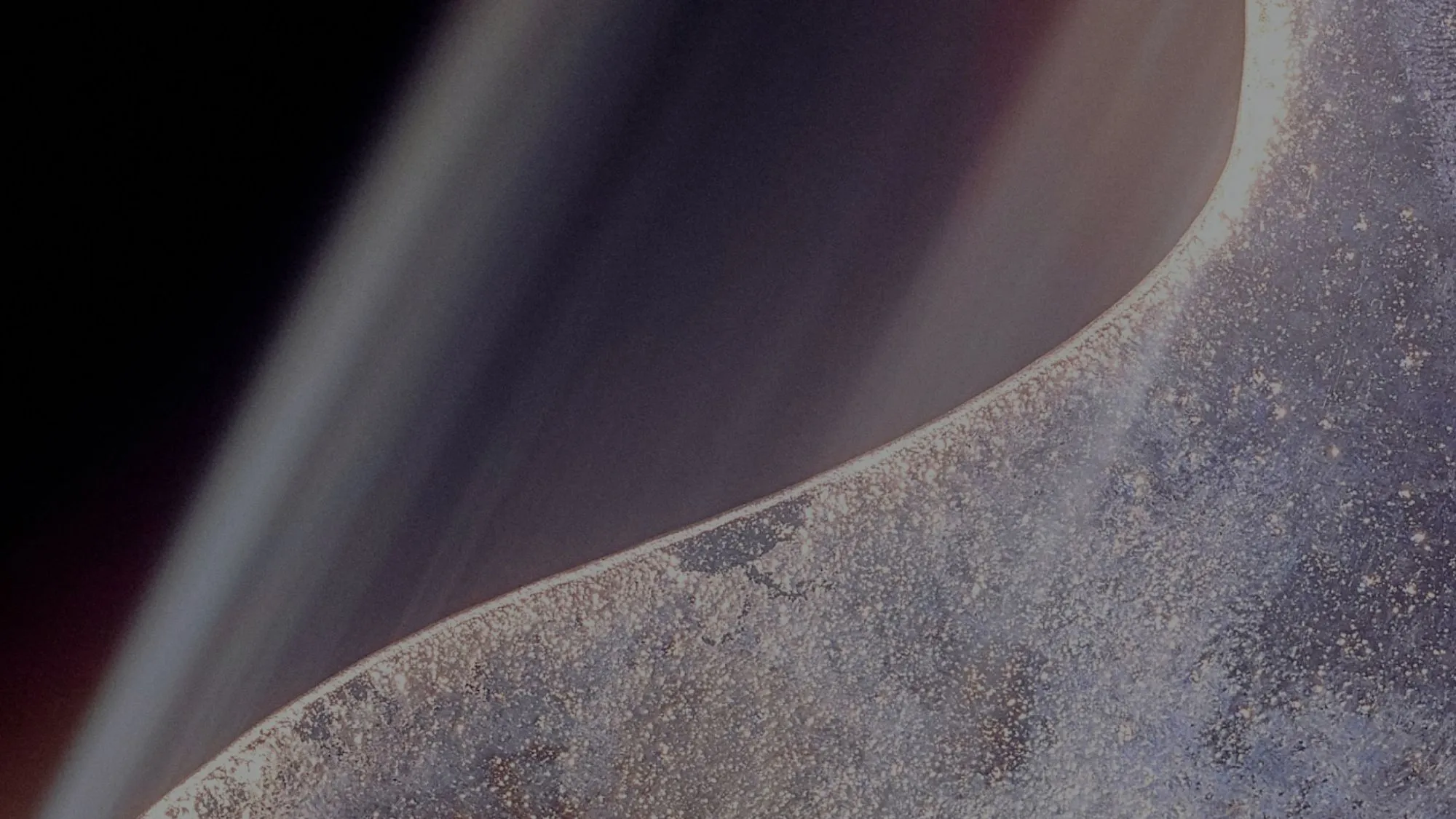 Close-up view of a planet's textured surface and a smooth, curved atmospheric layer against a dark background.