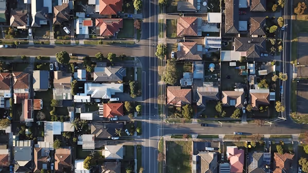 Aerial view of a suburban neighborhood with houses, roads, and trees in an organized grid pattern.