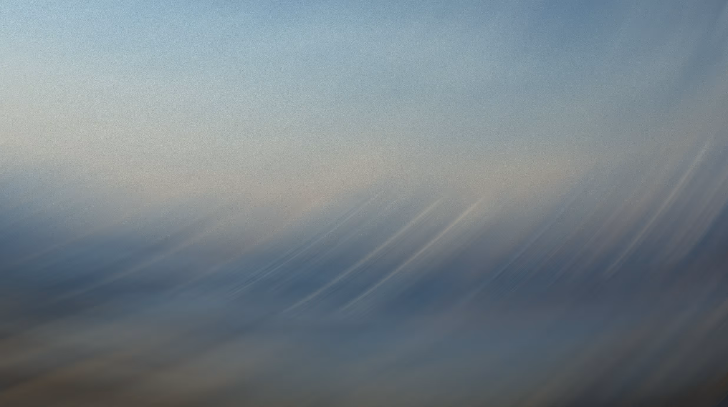 Abstract blurred gradient with soft streaks of blue, gray, and beige tones.