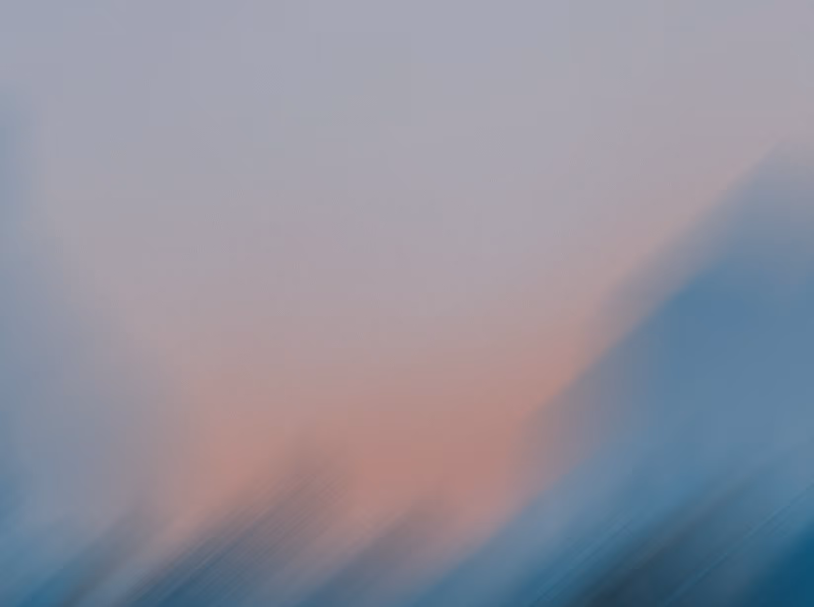 Abstract blur gradient featuring soft pink and blue hues blending diagonally.