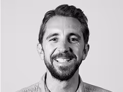 Smiling man with beard and short hair in black and white portrait.