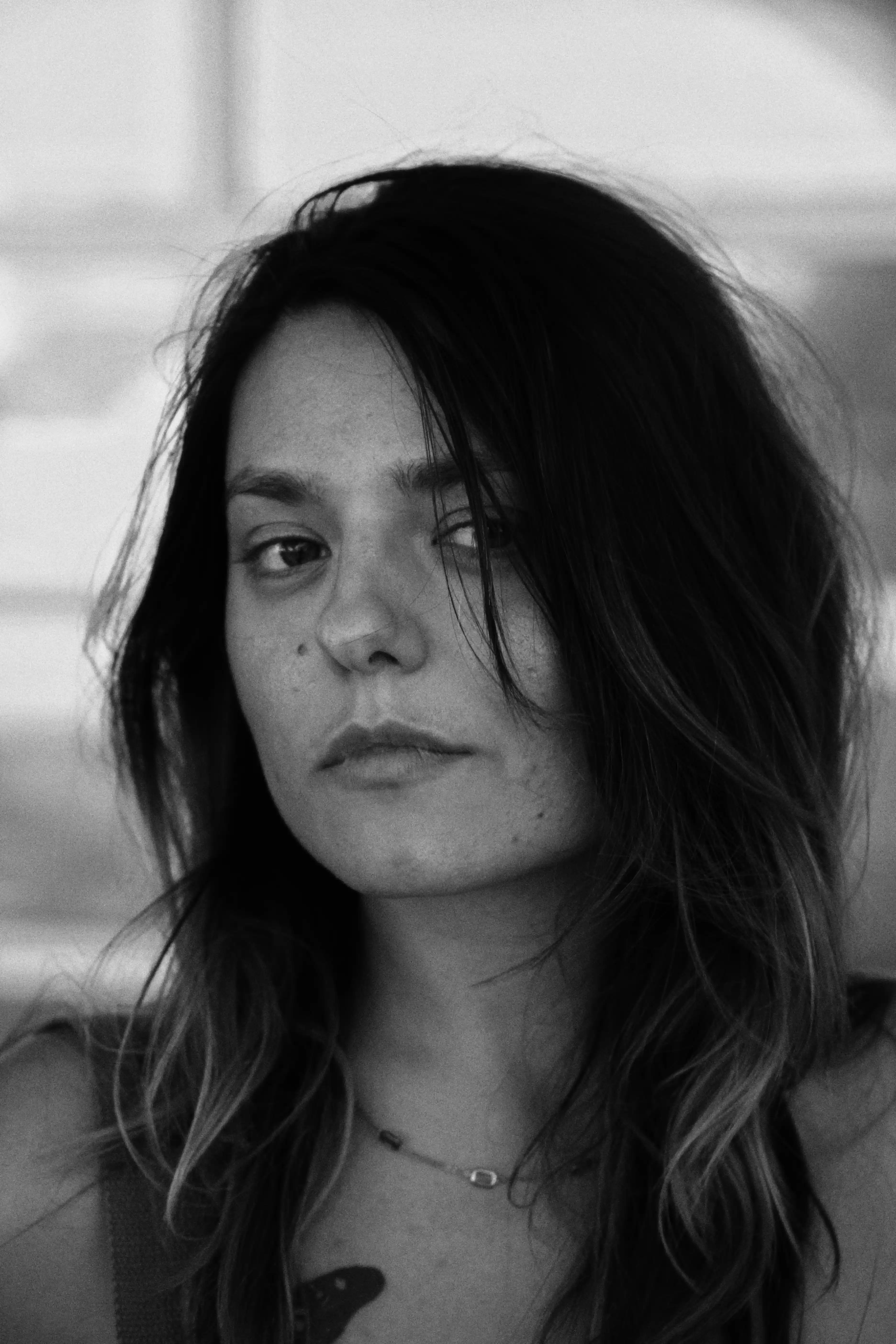 Black and white portrait of a woman with long hair looking slightly to the side with a neutral expression