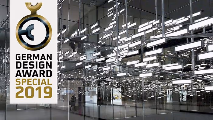 German Design Award Special 2019 logo displayed in modern glass building interior with bright lights.