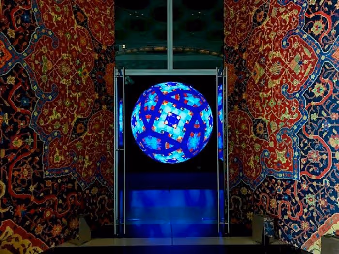 Glowing blue LED sphere displayed in glass case between ornate patterned fabric walls