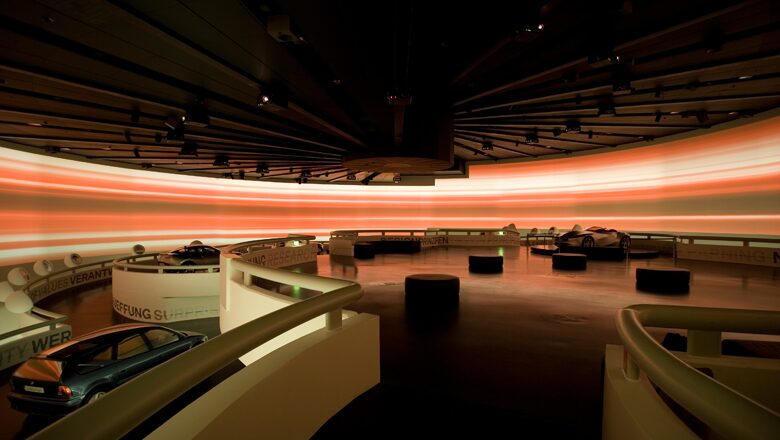 Modern museum exhibition space with orange neon light installation and vintage artifacts displays