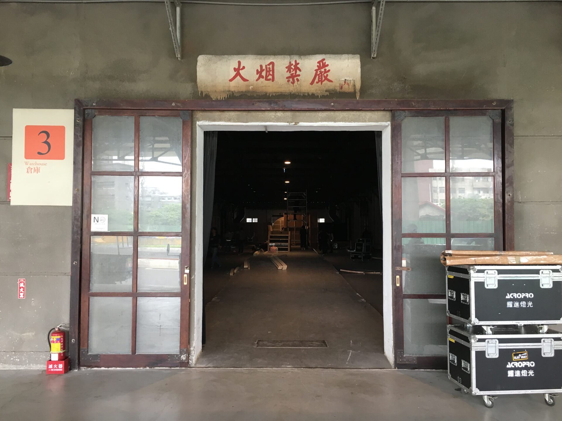 Industrial warehouse entrance with red door, Chinese characters above, number 3 sign.