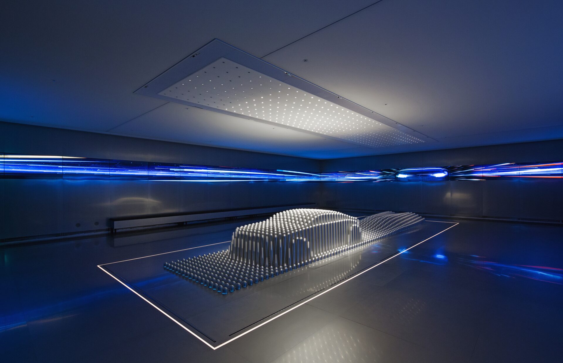 Modern futuristic interior with illuminated 3D sculptural object, blue ambient lighting, and minimalist architecture.