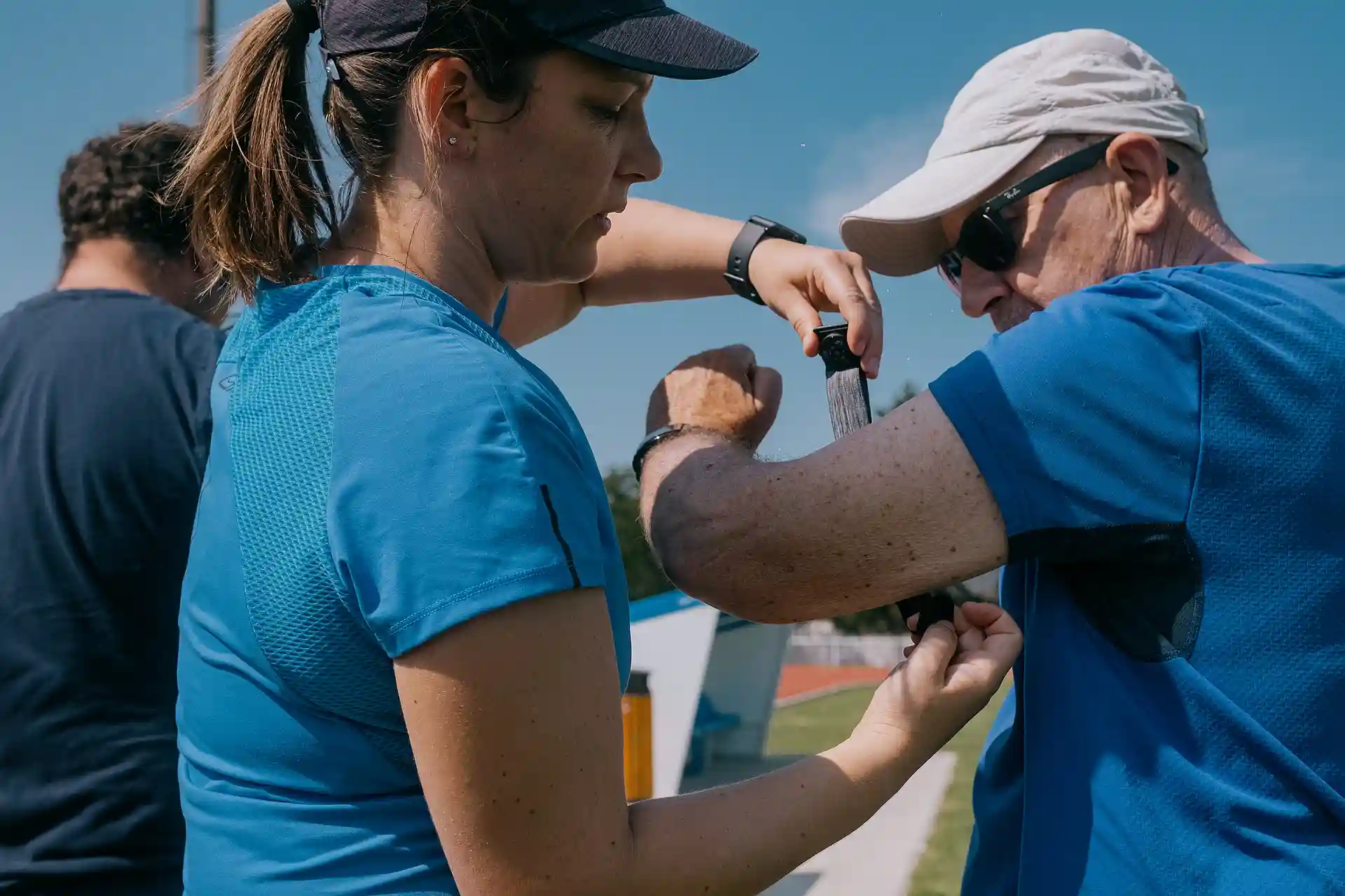 Une femme aide un homme à attacher un capteur de fréquence cardiaque autour de son bras lors d'une activité de rugby santé
