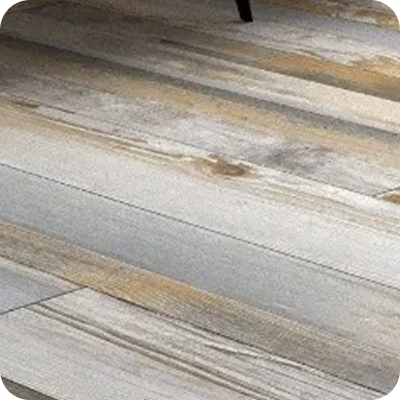 Close-up of a wooden floor with grey and beige planks showing natural wood grain and knots.