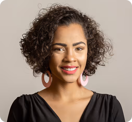 Smiling woman with short curly hair wearing large pink earrings and a black top.