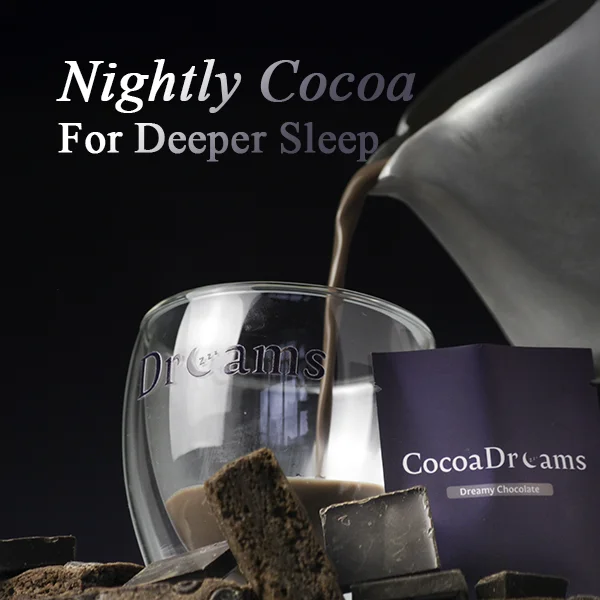 Hand holding a purple CocoaDreams packet labeled 'Dreamy Chocolate' among pieces of chocolate and cocoa powder.