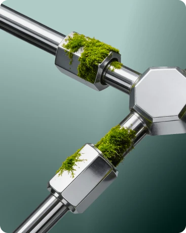Close-up of metallic pipes connected with hexagonal joints partially covered in green moss.