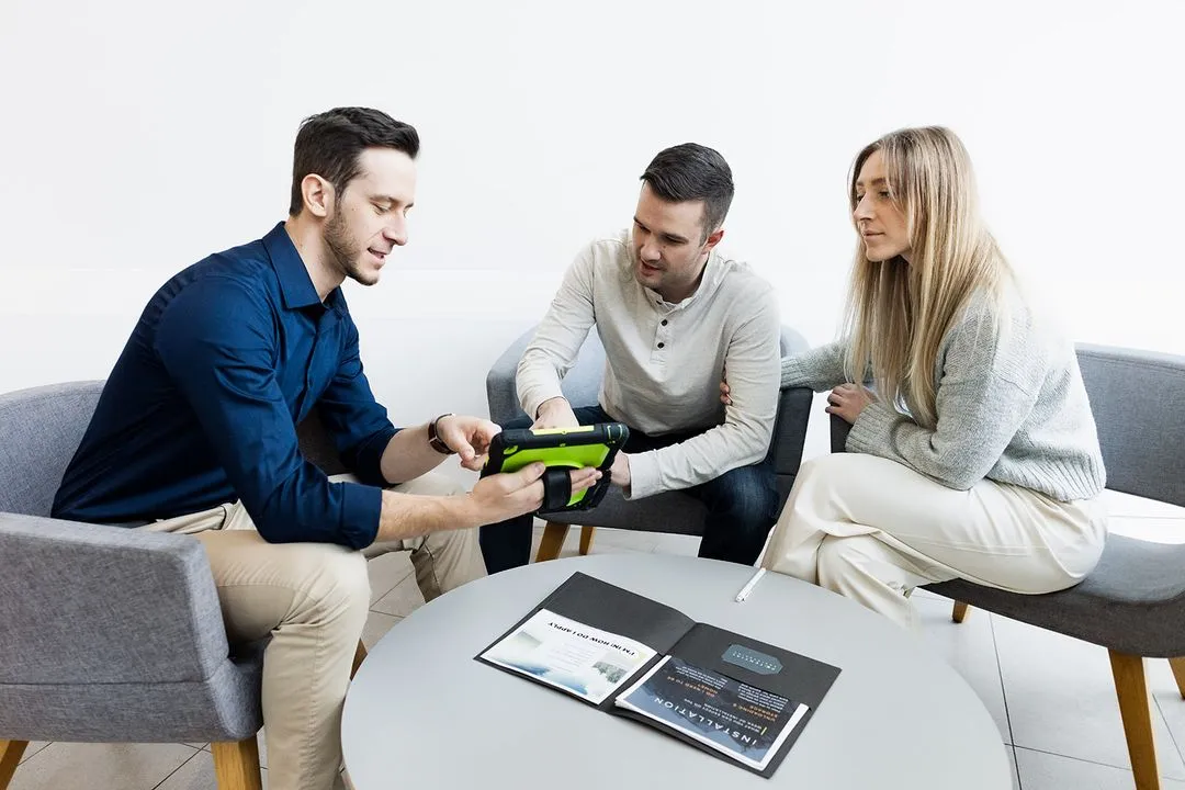 Couple sitting looking at a man showing them an app on an ipad