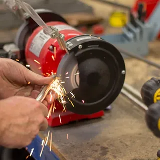 Person using a grinder to create sparks on a metal object in a workshop.